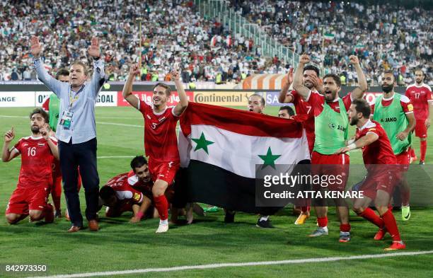 Syria's players celebrate at the end of their FIFA World Cup 2018 qualification football match against Iran at the Azadi Stadium in Tehran on...