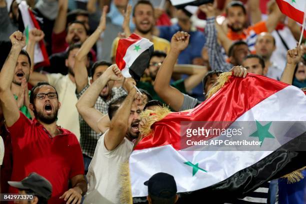 Supporters of Syria celebrate at the end of the FIFA World Cup 2018 qualification football match between Iran and Syria at the Azadi Stadium in...