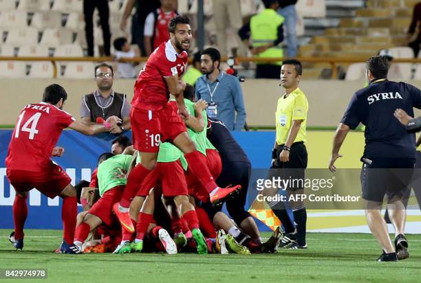 Syria's players celebrate at the end of their FIFA World Cup 2018 qualification football match against Iran at the Azadi Stadium in Tehran on...