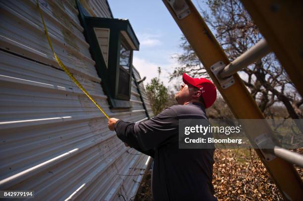 State Farm catastrophe claims adjuster measures the exterior of a home affected by Hurricane Harvey in Rockport, Texas, U.S., on Saturday, Sept. 2,...