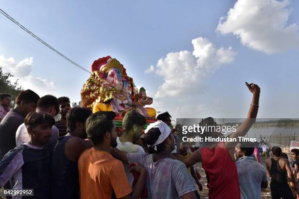 Devotees carry an idol of Lord Ganesha to immerse it into the Yamuna River, near ISBT during the last day of the Ganesh Chaturthi festival on...