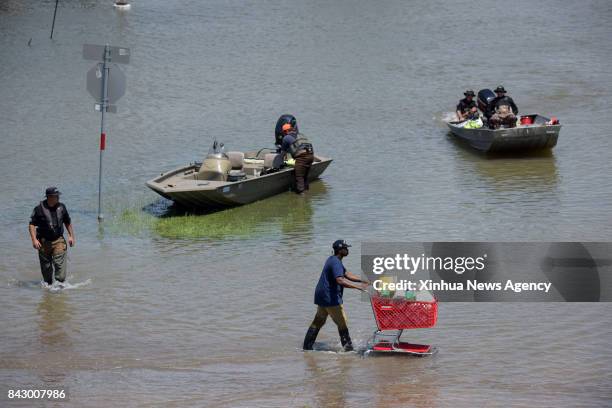 Aug. 31, 2017 -- A man walks by rescuers on a flooded road in Port Arthur, Texas, the United States, Aug. 31, 2017. Nearly 40 people died or are...