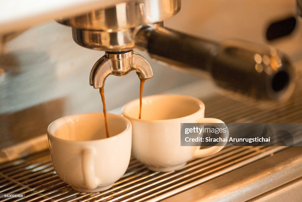 Coffee drips into two coffee cup from Espresso Machine
