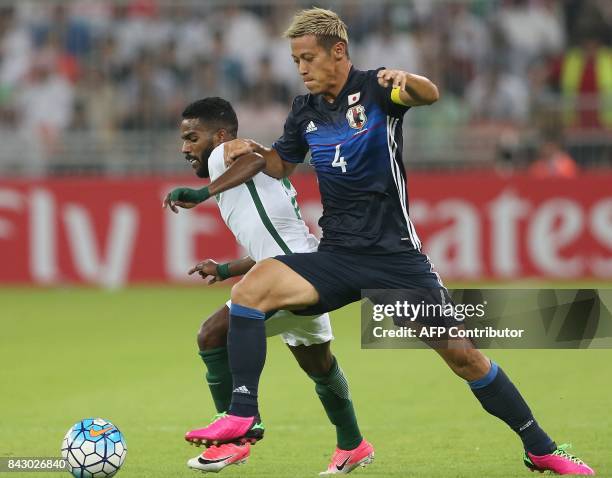 Saudi Arabia's Nawaf Alabid runs with the ball in front of Japan's Keisuki Honda during the FIFA World Cup 2018 qualification football match between...