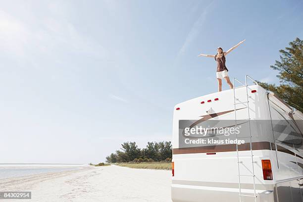 young woman standing on top of motor home - rv beach foto e immagini stock