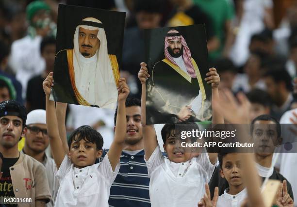 Saudi Arabia's fans hold up portraits of Saudi King Salman and Crown Prince Mohammed bin Salman during the FIFA World Cup 2018 qualification football...