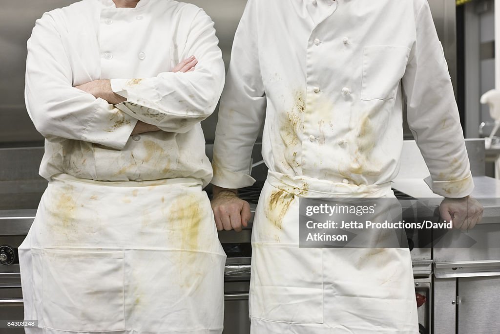 Dirty chefs leaning against stove