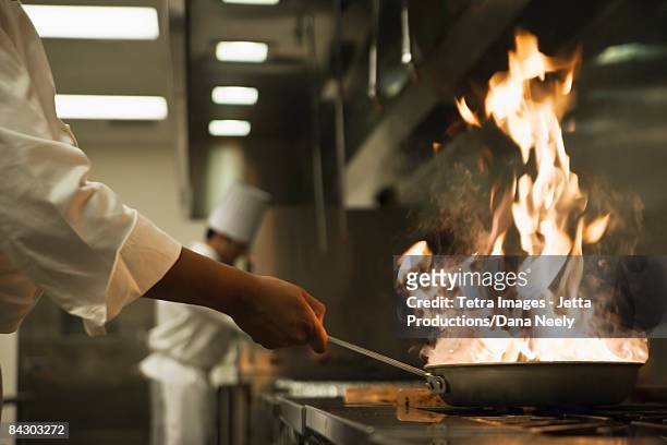 chef holding flaming pan - restaurant kitchen ストックフォトと画像