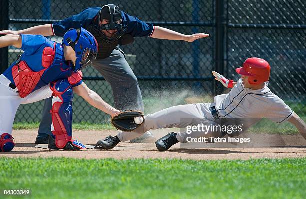 baseball player sliding into home plate - baseballmannschaft stock-fotos und bilder
