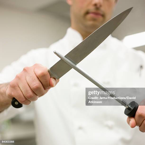 chef sharpening knife in kitchen - afilado fotografías e imágenes de stock