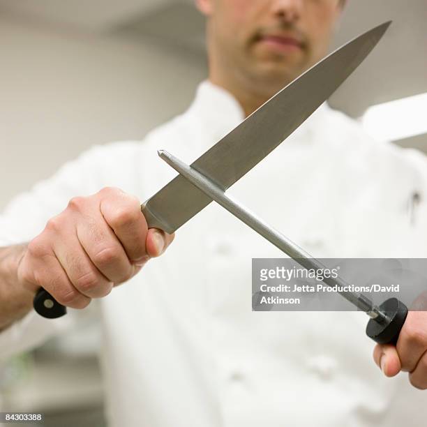chef sharpening knife in kitchen - kitchen knife stockfoto's en -beelden