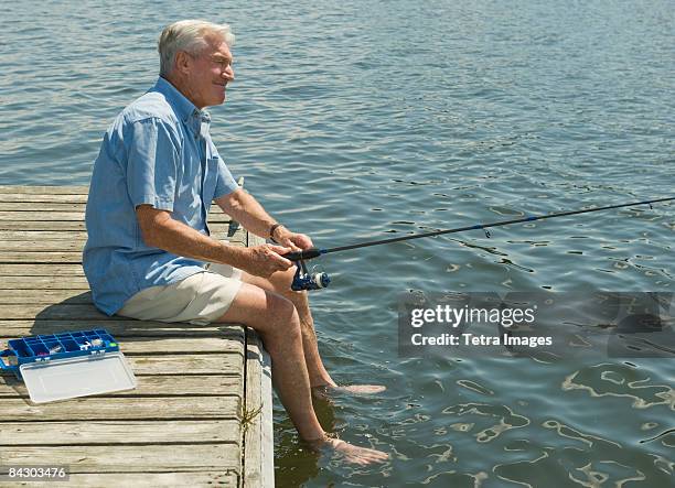 senior man fishing off dock - fishing rod stock-fotos und bilder