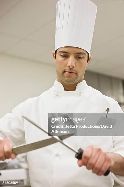 chef sharpening knife in kitchen - sharpening knife stock pictures, royalty-free photos & images