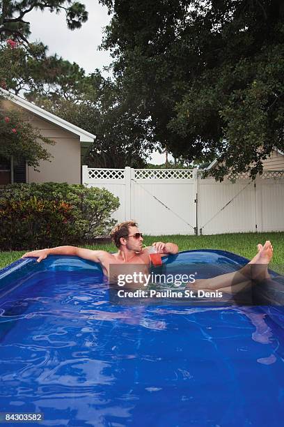 man relaxing in inflatable swimming pool - aufblasbarer gegenstand stock-fotos und bilder