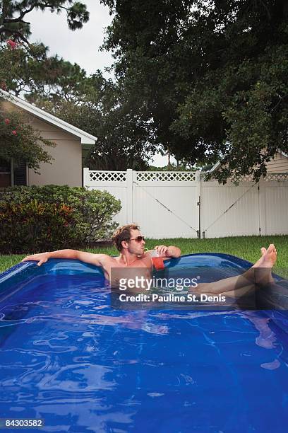 man relaxing in inflatable swimming pool - inflatable swimming pool stock pictures, royalty-free photos & images