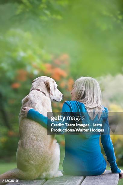 girl and dog sitting together on picnic table - yellow labrador retriever stock pictures, royalty-free photos & images