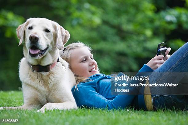 girl resting on dog in park - labrador stock-fotos und bilder