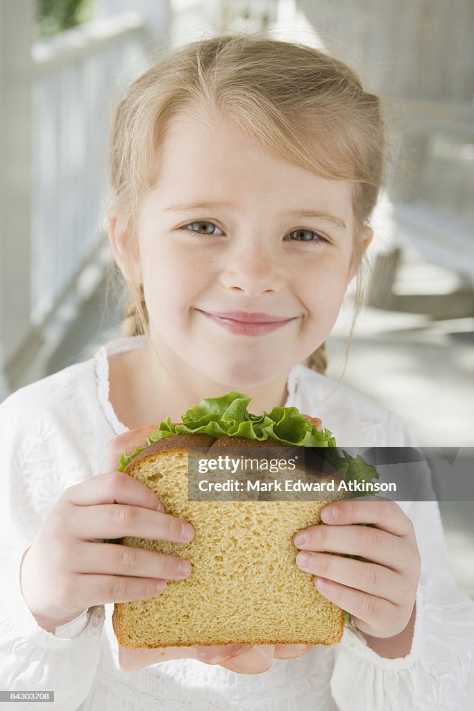 Girl eating sandwich on porch