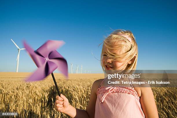 girl holding pinwheel on wind farm - the whirligig stockfoto's en -beelden
