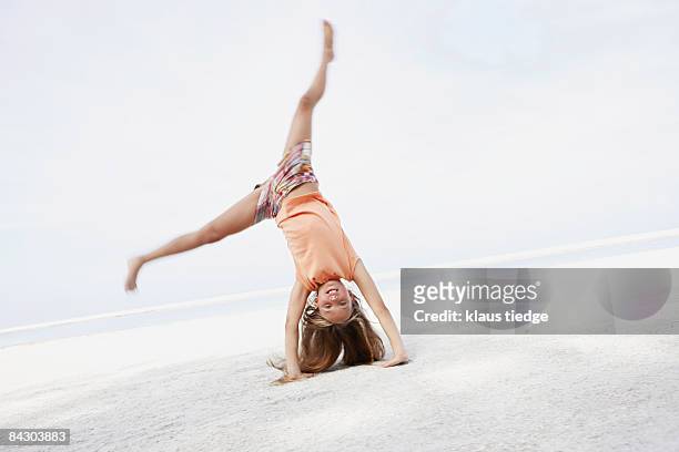 girl doing cartwheel on beach - équilibre sur les mains photos et images de collection