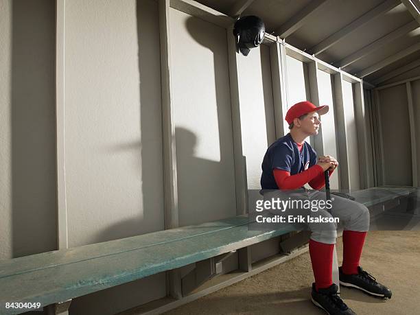 serious baseball player sitting in dugout - dugout stock pictures, royalty-free photos & images