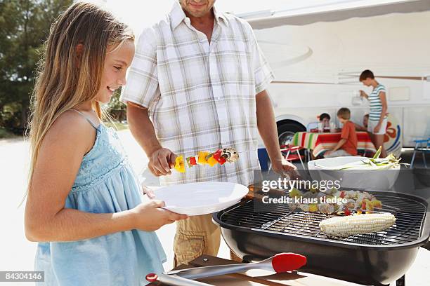 man grilling dinner for family on beach - grill zubereitung stock-fotos und bilder