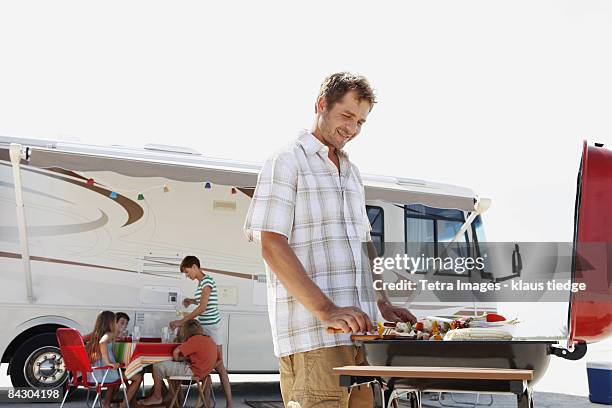 man grilling dinner for family on beach - rv beach stock pictures, royalty-free photos & images