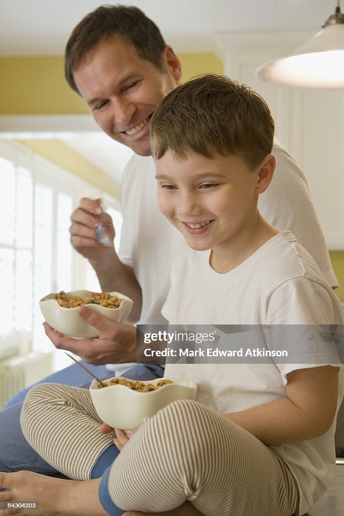 Father and son eating breakfast on kitchen counter