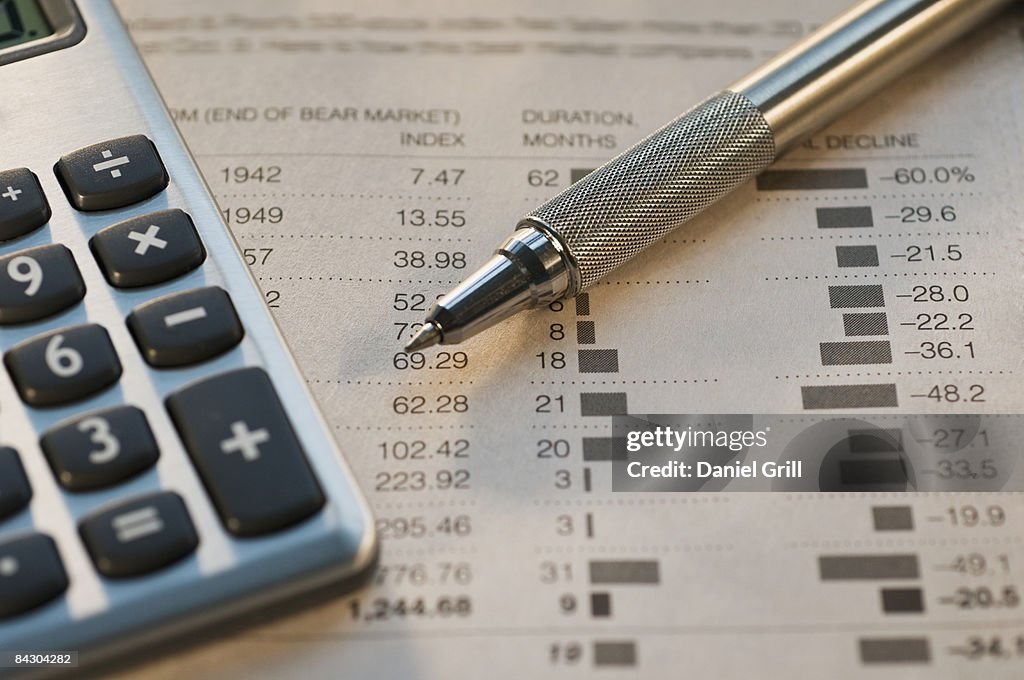 Close up of pen, calculator and financial pages