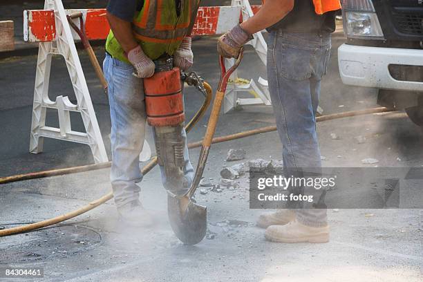 construction workers using jackhammer and shovel - presslufthammer stock-fotos und bilder