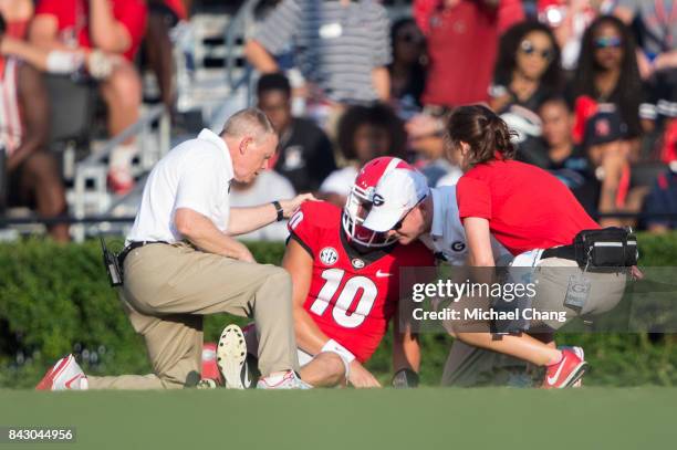 Quarterback Jacob Eason of the Georgia Bulldogs gets help from trainers after injuring his leg during their game against the Appalachian State...