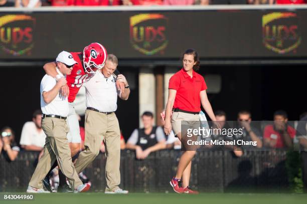 Quarterback Jacob Eason of the Georgia Bulldogs gets help from trainers after injuring his leg during their game against the Appalachian State...