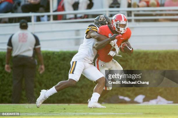 Defensive back Austin Exford of the Appalachian State Mountaineers looks to tackle running back Sony Michel of the Georgia Bulldogs at Sanford...
