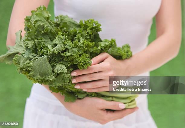 woman holding fresh kale - kale bunch stock pictures, royalty-free photos & images