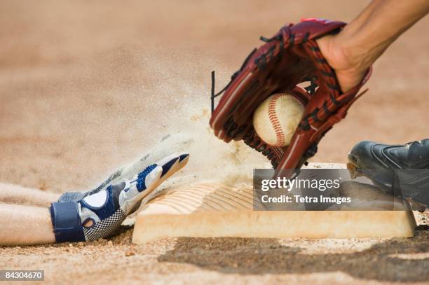 baseball player sliding into home base - baseball stock-fotos und bilder