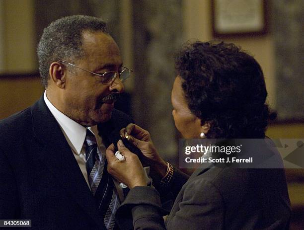 Newly sworn in Sen. Roland W. Burris, D-Ill., gets help putting on his Senate pin from wife Berlean M. Burris as they prepare for a mock swearing in...