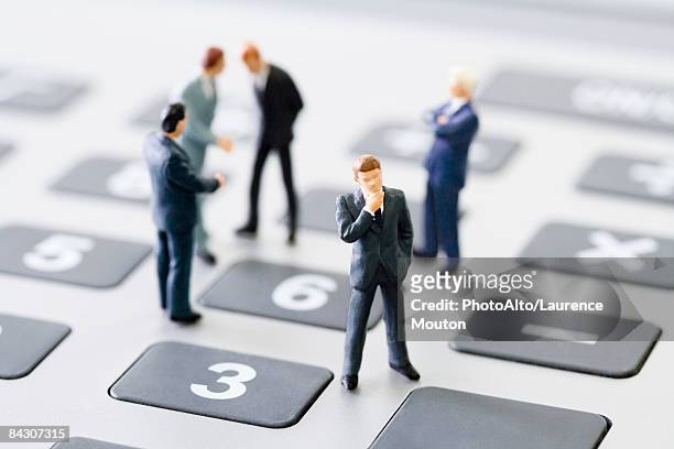 miniature businessmen standing on calculator - figurine bildbanksfoton och bilder