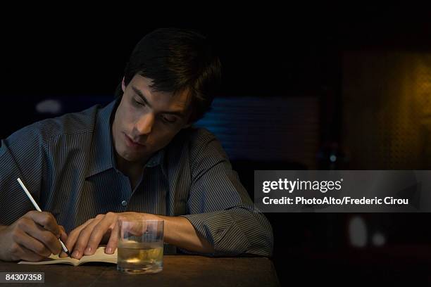man writing in notebook, sitting in bar - authors night stockfoto's en -beelden