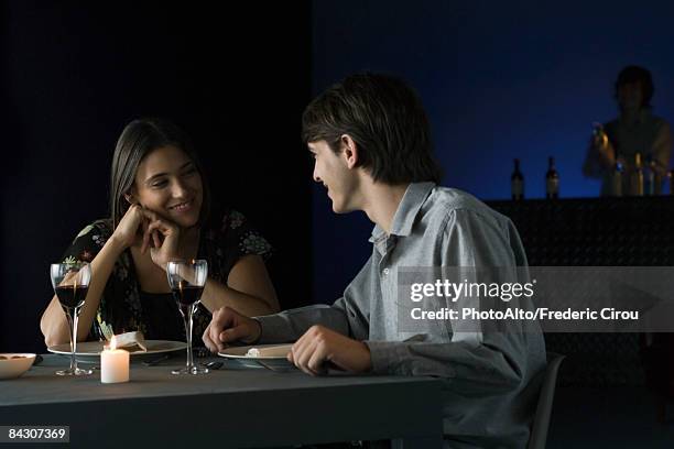 couple having conversation over dinner at restaurant, smiling at each other - couple dark background bildbanksfoton och bilder