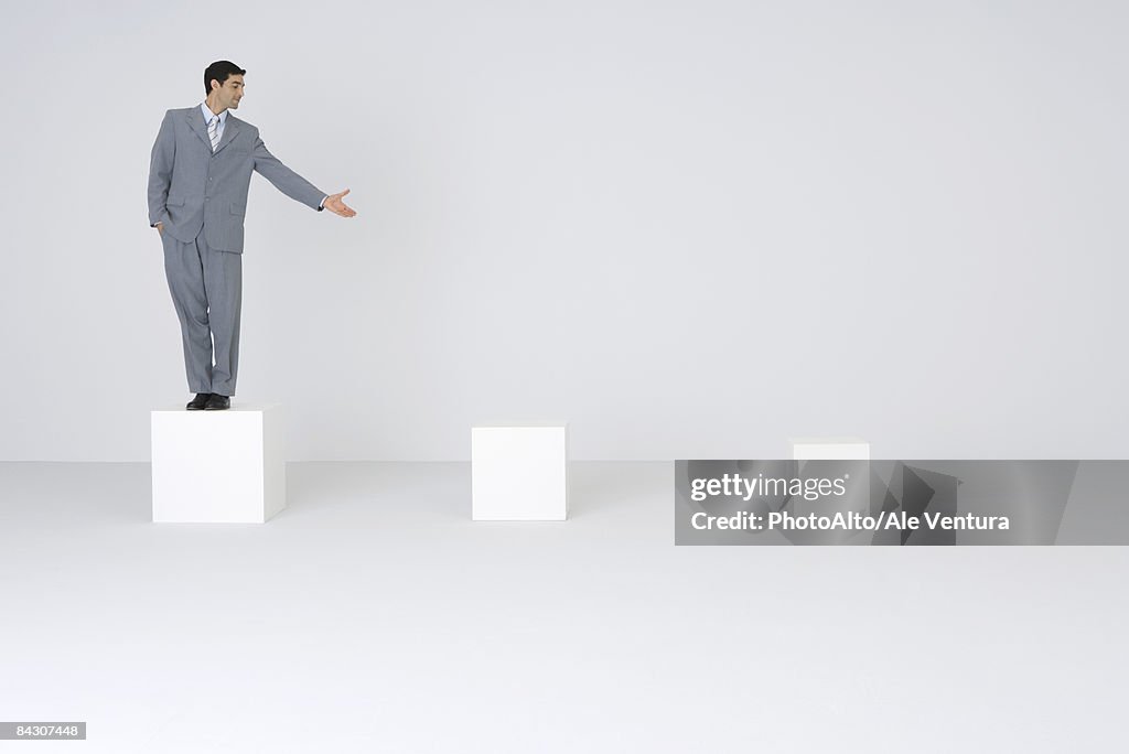 Businessman standing on pedestal, presenting empty pedestals