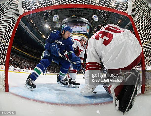 Ilya Bryzgalov of the Phoenix Coyotes covers the side of his net as Taylor Pyatt of the Vancouver Canucks looks for a rebound at the top of the...