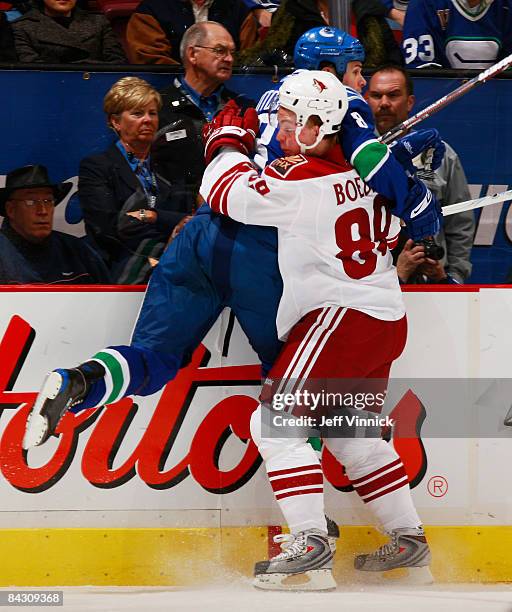 Willie Mitchell of the Vancouver Canucks hits Mikkel Boedker of the Phoenix Coyotes along the boards during their game at General Motors Place on...