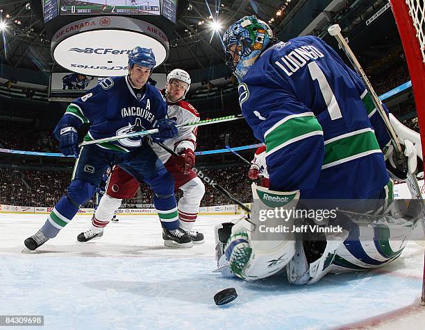 Willie Mitchell of the Vancouver Canucks keeps Joakim Lindstrom of the Phoenix Coyotes from crashing the net while teammate Roberto Luongo reaches...