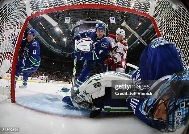 Roberto Luongo of the Vancouver Canucks lays in his crease after making a stop with teammates Willie Mitchell and Mats Sundin keep Steven Reinprecht...