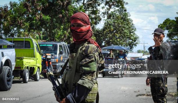 In this photo taken on September 5, 2017 shows a Moro Islamic Liberation Front rebel with face covered, along with a government soldier manning a...