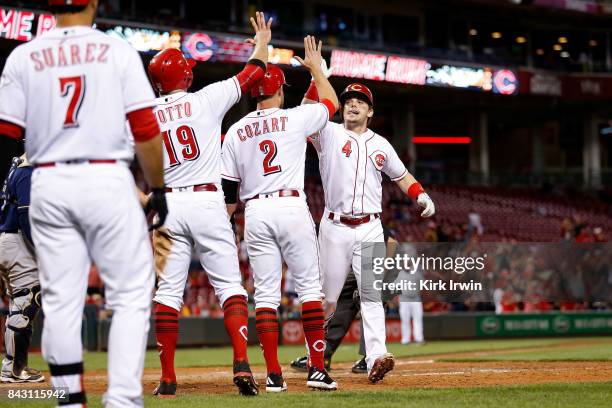 Scooter Gennett of the Cincinnati Reds is congratulated by Zack Cozart of the Cincinnati Reds and Joey Votto of the Cincinnati Reds after hitting a...