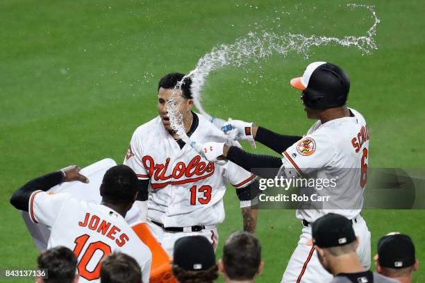 Manny Machado of the Baltimore Orioles is doused with water by Adam Jones and Jonathan Schoop after hitting a two RBI walk off home run to give the...