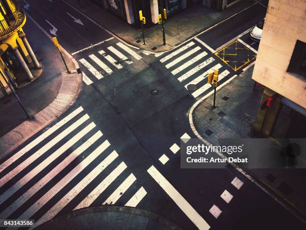 road intersection in city taken from high angle view without people, nice street geometry and white crosswalk in contrast of black asphalt. - crossroad top view stock-fotos und bilder