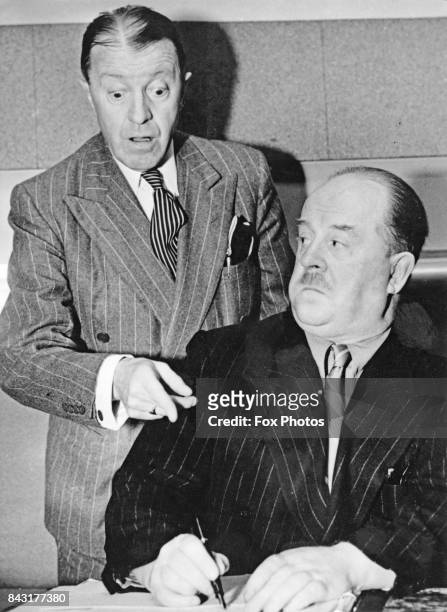 British comedian Tommy Handley , star of the BBC radio comedy 'It's That Man Again' or 'ITMA', with the show's writer Ted Kavanagh , circa 1940.