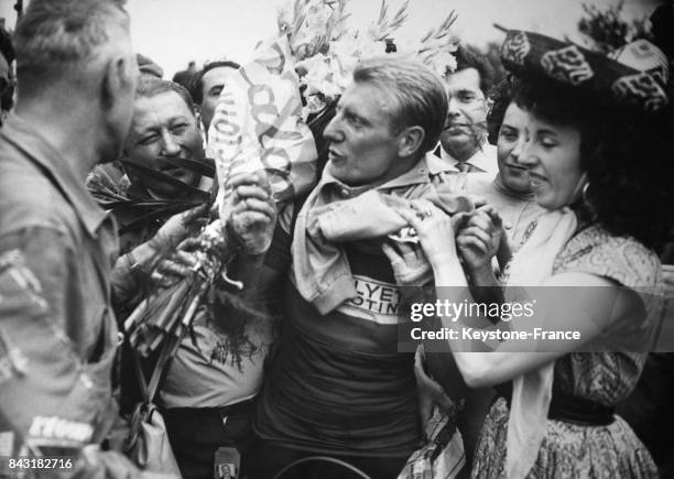 André Darrigade, vainqueur de la 1ère étape Reims-Liège du Tour de France 1956, endosse le maillot jaune, aidé par Yvette Horner, à Liège, Belgique,...